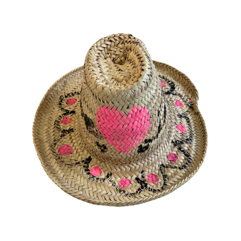 Top view of a hand-painted straw hat with a pink woven heart and black floral motifs handpainted by Kerri Rosenthal
