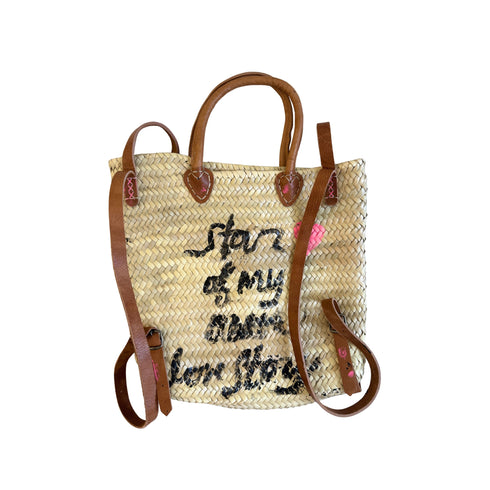 Back view of a hand-painted straw tote bag with 'Star of my own love story' script and tan leather handles handpainted by artist Kerri Rosenthal
