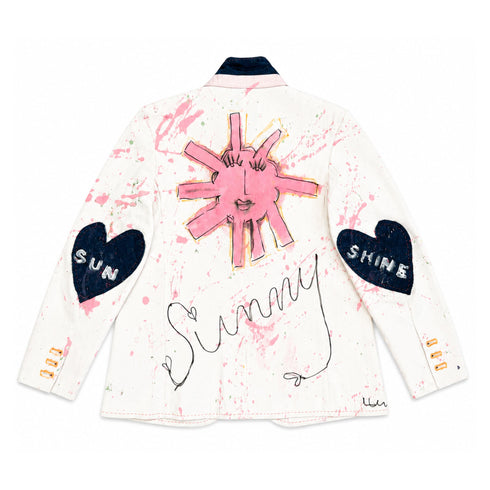 White hand-painted jacket with navy collar, featuring a pink sun face design on the back, black heart elbow patches reading 'Sun' and 'Shine,' pink paint splatters, and 'Sunny' script across the back — Kerri Rosenthal wearable art