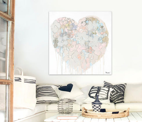 Heart-shaped abstract art print on a wall above an outdoor area with sofa with decorative pillows.