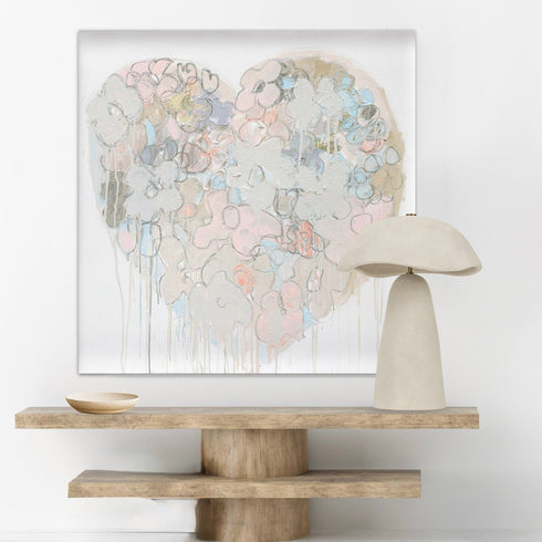 Decorative table with a large abstract painting and a modern lamp against a white wall.