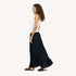 Side view of model wearing a pale pink tank top and a black tiered maxi skirt, paired with woven black flats. Women's clothing by Kerri Rosenthal