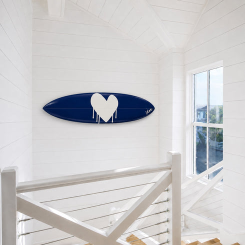 Kerri Rosenthal navy heart surfboard mounted horizontally on a wall near a staircase landing