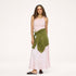 Model wearing a pale pink ribbed tank with a heart pendant necklace, an olive green cardigan tied around the waist, a blush satin maxi skirt, and black woven flats. Shop Kerri Rosenthal