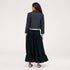 Back view of model wearing a navy pinstriped cropped blazer with heart-embroidered elbow patches over a black tiered maxi skirt