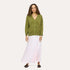 Woman wearing a Kerri Rosenthal olive green v-neck knit cardigan with chartreuse buttons, styled with a blush pink maxi skirt and black woven loafers.