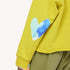 Close up of chartreuse sweatshirt with a blue heart elbow patch, and olive pants.