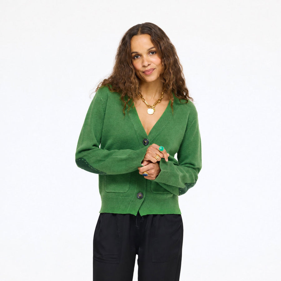 Model wearing the Frances Cardigan in evergreen with black pants, hands clasped, front view