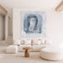 Large square abstract painting buy artist, Kerri Rosenthal in shades of blue, gray, and white hanging on a neutral wall above a low-profile cream modular sofa with wavy-lined accent pillows.