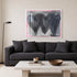 Holding Hearts art print by Kerri Rosenthal with three black hearts and grey ground and pink outline in a white frame displayed on a living room wall with black couch.