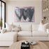 Kerri Rosenthal painting framed in plexi with 3 black connecting hearts and gray and pink background texture and brushstrokes on Holding Hearts art print on canvas. Family room with white couch and Kerri Rosenthal Wanderlust pillow.