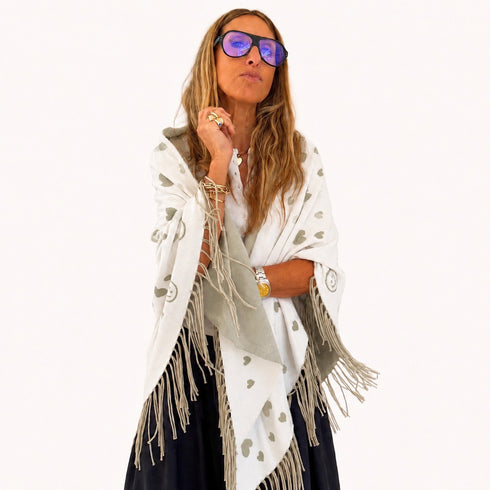 Woman wrapped in a cream fringed poncho with a heart pattern