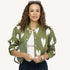Woman wearing an olive green quilted bomber jacket with heart print, white top, and sunglasses on her head.
