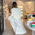Kerri standing in the Westport flagship shop wearing a white open-knit crochet cardigan with large neon yellow-green trim and heart on the back and white flowy maxi dress.