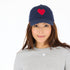 Navy blue cotton baseball cap hat with a unique Imperfect heart patch and an adjustable belt pull for a customized fit by Kerri Rosenthal