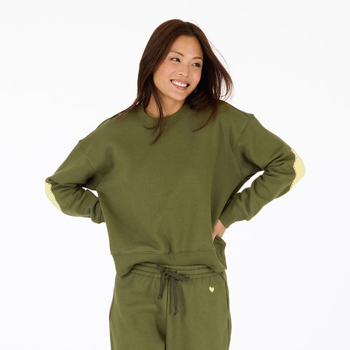 Classic green cotton fleece sweatshirt with Loved graphic at back neck and contrast imperfect heart elbow patches by Kerri Rosenthal.