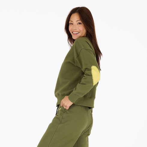Classic green cotton fleece sweatshirt with Loved graphic at back neck and contrast imperfect heart elbow patches by Kerri Rosenthal.