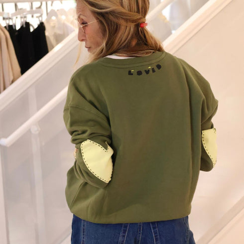 Classic green cotton fleece sweatshirt with Loved graphic at back neck and contrast imperfect heart elbow patches by Kerri Rosenthal.