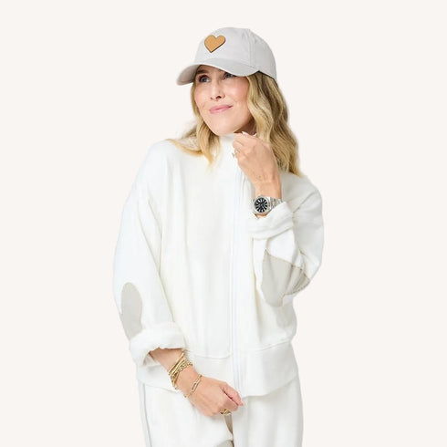 Zip-up mock neck cream sweatshirt in cotton loop terry with heart-tonal elbows and grey baseball cap hat by Kerri Rosenthal