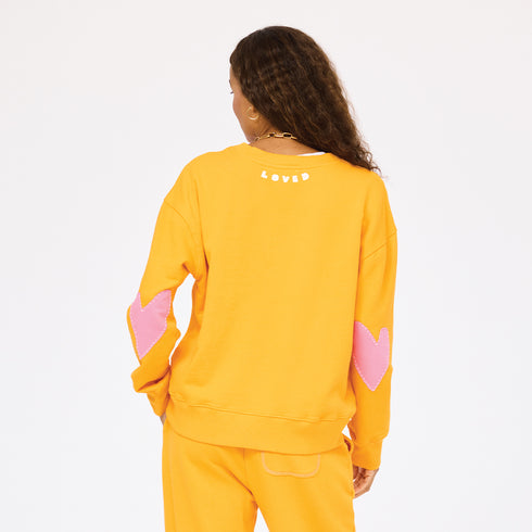 Ex-Boyfriend orange sweatshirt in 100% cotton terry with heart elbow patches and 'Loved' graphic by Kerri Rosenthal