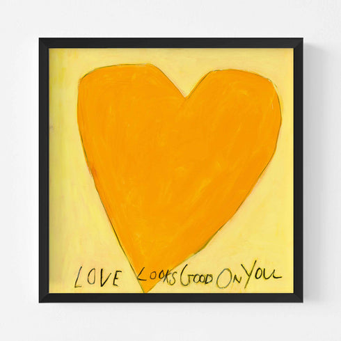 Love Looks Good on You art print: a bold orange heart with an angular shape on a pale yellow background, with "Love Looks Good On You" hand-painted below it in black, in a black frame