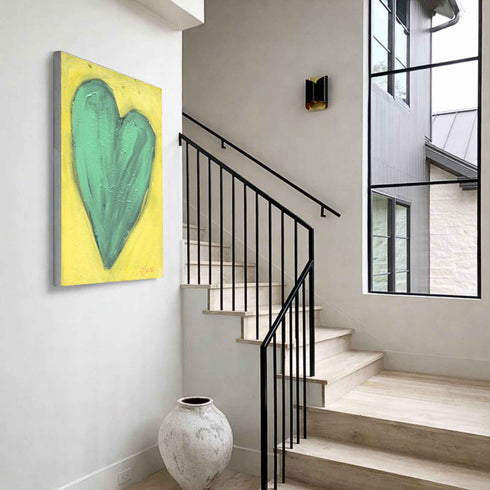 Love Note 2 art print: a tall green-teal heart with thick textured brushstrokes on a bright yellow background, signed in pink, hung in a room setting