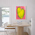 Love Note 4 art print: a tall yellow-green heart with a light outline on a bright pink background, hung in a room setting