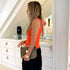 Bright orange ribbed tank top styled with black skirt and olive green clutch
