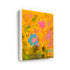 Wild Love Garden art print: a golden-orange field layered with a blue flower with a pink center, a pink blossom, olive-green patches and loose black handwritten marks, printed on stretched canvas and shown at an angle