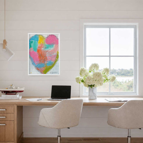 Wish Upon a Heart art print: a colorful pastel heart in a white frame, hung on a white shiplap wall above a wooden desk with white hydrangeas beside a bright window