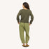 Back view of a woman wearing an olive green knit sweater, green pants, and tan suede loafers.