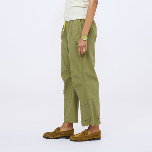 Side view of olive green drawstring pants with a cream top and tan suede loafers.
