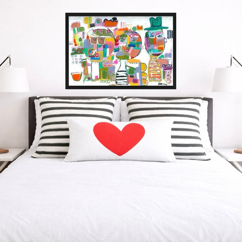 Bedroom with a bed featuring striped pillows and a heart-shaped pillow, framed artwork above, and two lamps on either side.