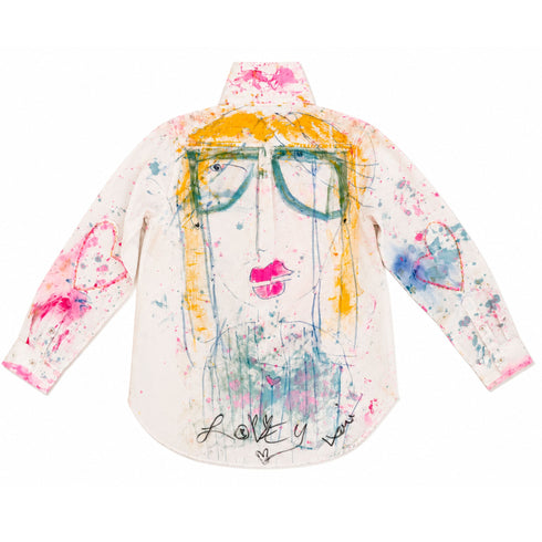 White button-down shirt hand-painted on the back with a whimsical face featuring round glasses, yellow hair, and pink lips, heart outlines on both sleeves, pink and blue paint splatters throughout, and 'Lovey' script at the hem — Kerri Rosenthal wearable art