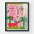 Whimsical pink face portrait painting in black wood frame, playful abstract faces with palm tree details and beaded necklace accent