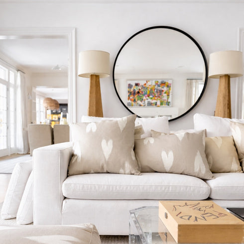 Modern living room with a white sofa, decorative square throw pillows, and a clear glass coffee table.
