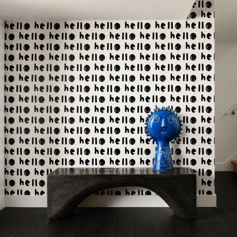 Blue decorative object on a black shelf against a wall with 'hello' pattern