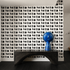 Blue decorative object on a black shelf against a wall with 'hello' pattern