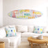 Decorative surfboard with colorful text above a white sofa in a living room.