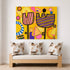 A colorful abstract canvas print featuring stylized tulips and geometric shapes in yellow, pink, purple, orange, and black, displayed on a white wall above a light wood bench with three patterned throw pillows.