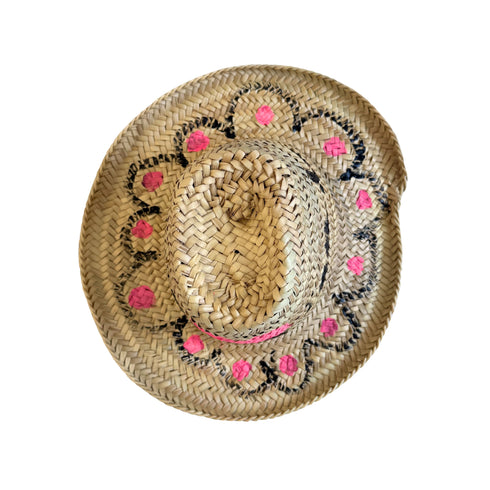 Top view of a hand-painted straw hat with a pink woven heart and black floral motifs handpainted by Kerri Rosenthal