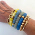 Wrist wearing multiple beaded bracelets with gold accents on a white background