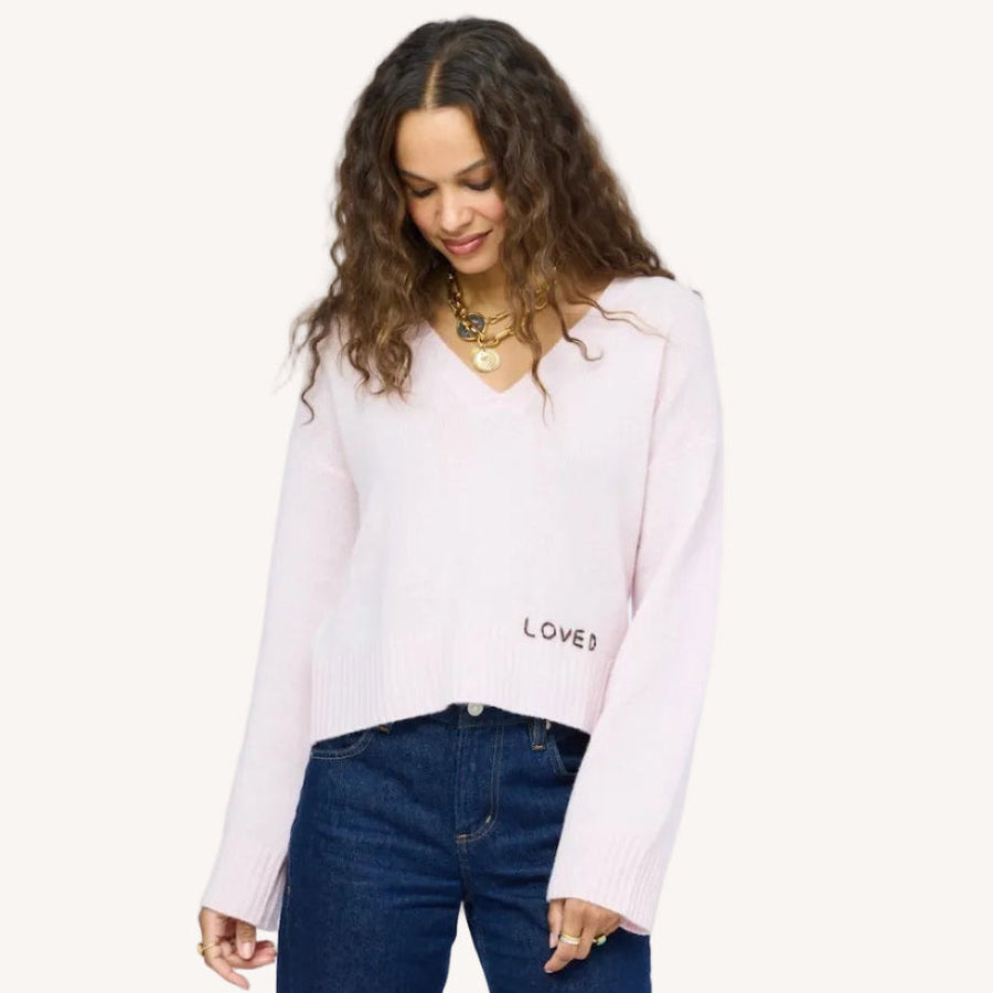 Model wearing Saturday V-Neck, an easy, relaxed-fit 100% cashmere sweater in hardly pink with hand-stitched "Loved" embroidery on hem.
