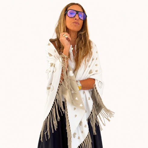 Woman wrapped in a cream fringed poncho with a heart pattern