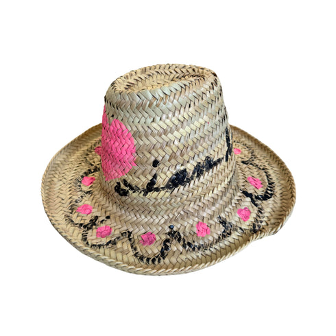 Side view of a hand-painted straw hat with pink and black floral and heart motifs handpainted by Kerri Rosenthal