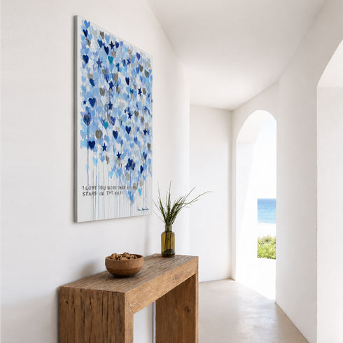 Blue heart and star watercolor painting displayed in bright white hallway entryway with console table and potted plant
