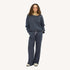 Woman wearing a charcoal sweatshirt with 'loved' embroidered on neckline and matching sweatpants and sunglasses.