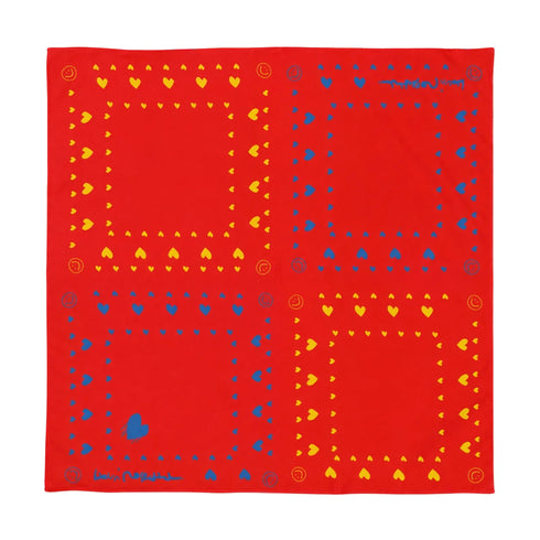 A square red bandana featuring a geometric pattern of four large panels, each bordered with yellow hearts and blue dots and small decorative motifs.