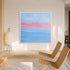 A square framed abstract painting hanging on a beige wall in a modern room. The artwork features a soft blue sky with a vibrant pink horizon and horizontal blue bands below.