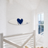 Kerri Rosenthal navy heart surfboard mounted horizontally on a wall near a staircase landing